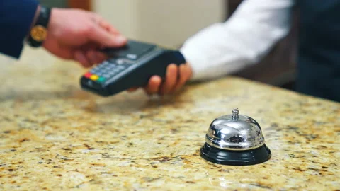 Guest makes card payment at check-in. Bell at hotel reception. Stock Footage 147621048