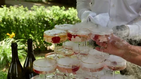 Guest taking a steaming cocktail from a champagne tower outdoors. Stock Footage 342510100