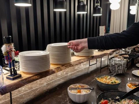 Guest taking a white plate from a stack at a holiday hotel breakfast buffet Stock Photos