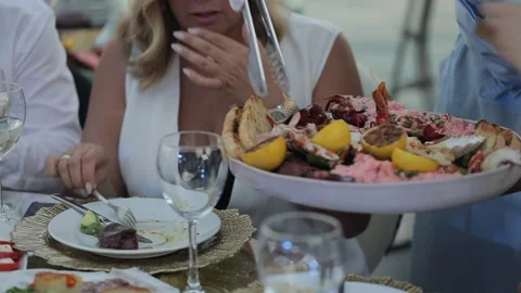 The guests at the banquet table is having dinner, the waiter is serving food Stock Footage 138903186