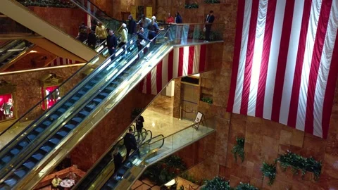 Guests move up and down escalators inside Trump Hotel lobby, capturing luxury Stock Footage 337739358