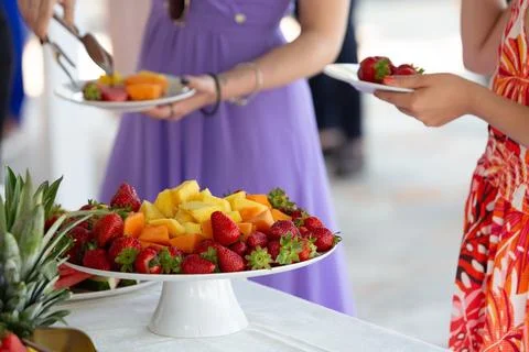 Guests picking fresh fruit from buffet table at event 库存照片