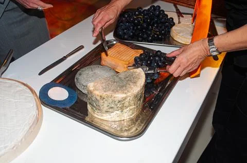 Guests Serving Aged Cheese and Grapes on a Silver Platter at a Party Buffet Stock Photos