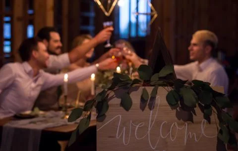 Guests sit at festively decorated table. Guests raised their glasses. Foto stock