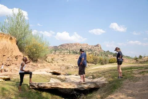Guide explaining to tourist at river the dinosaur tracks found in the rocks Stock Photos