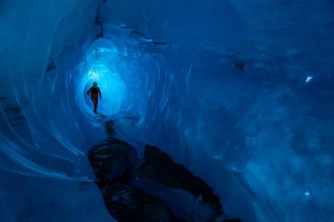 Guide inside an ice cave on a glacier in Alaska. Glacier caves are rare on te Stock Photos