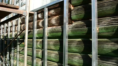 Guide metal strips on an old log wall, preparation for facing the house Stock Footage 148010966