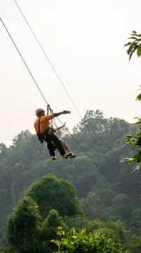 Guide taking a selfie in the air in a Zip line with green vegetation in the.. Stock Photos