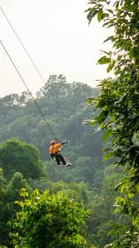 Guide taking a selfie in the air in a Zip line with green vegetation in the.. 스톡 사진