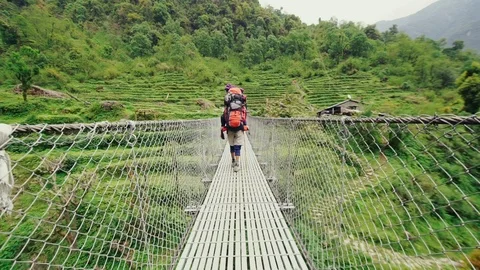 Guide walking over hanging rope bridge with backpack. Stock Footage 89676650