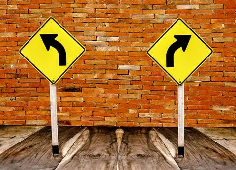 The guidepost  turn left and turn right on wood floor and old brickwall backg Stock Photos