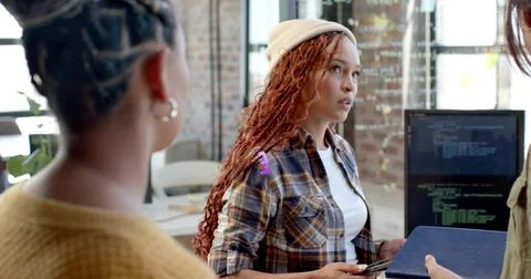 Guiding discussion around code on screen in office, beanie-clad woman with sm Foto stock