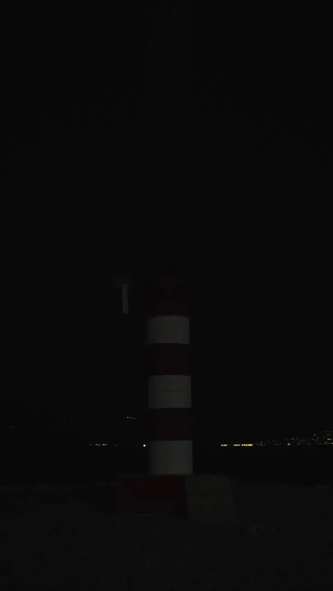 Guiding light shines through the night at a coastal harbor Stock Footage 296188114