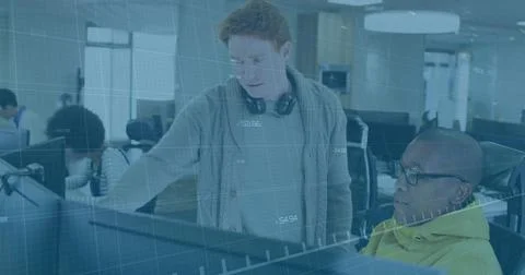 Guiding red-haired developer collaborating with hoodie engineer at open-plan Foto stock