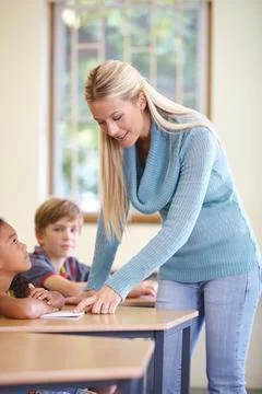 Guiding them in their learning. A young teacher helping her students during a Stock Photos