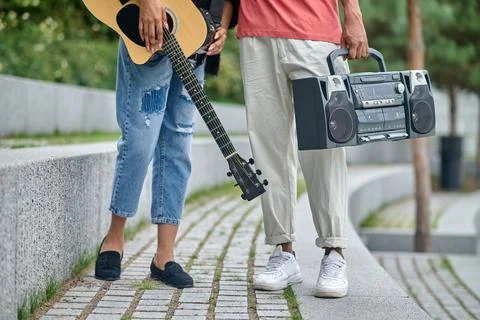 Guitar and record-player in hands of young people Stock Photos