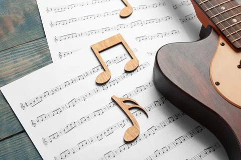 Guitar and sheets with music notes on wooden table Stock Photos