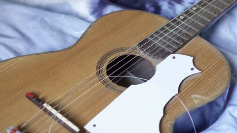 Guitar with broken string resting on the bed Stockbeeldmateriaal 118259508