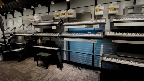 Guitar Center retail store interior pan of keyboards and person leaving scene Stock Footage 170341592