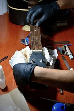 Guitar Luthier Installing New String on Acoustic Guitar Headstock and Fretboard 库存照片