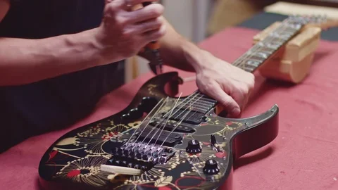 Guitar maker cut and remove old strings from electric guitar Stock Footage 117985314