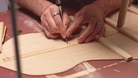 Guitar maker cuts braces to insert horizontal braces in acoustic guitar Stock Footage 117975286
