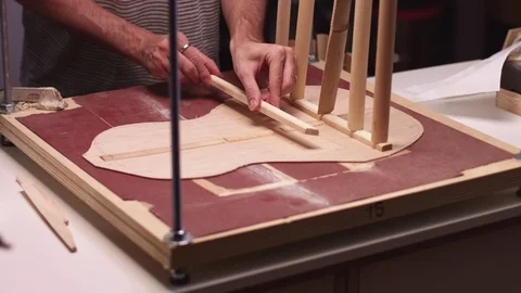 Guitar maker insert braces on guitar soundboard Stock Footage 117977013