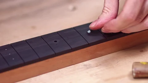 Guitar maker inserts position marker in guitar neck Stock Footage 122029585