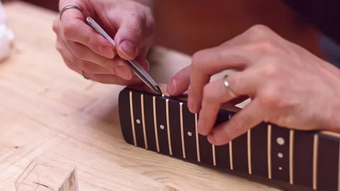 Guitar maker inserts position marker in guitar neck Stock Footage 122030864