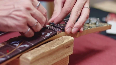 Guitar maker put new strings on electric guitar Stock Footage 117987169