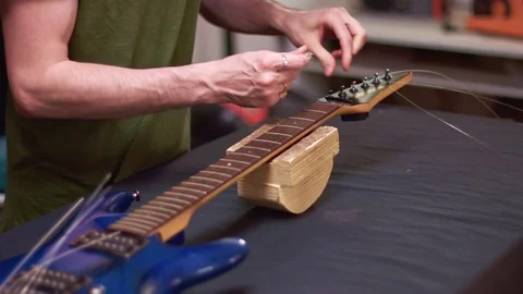 Guitar maker repairs guitar string, slow motion Stock Footage 113064581