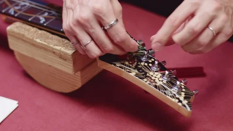 Guitar maker wrap string with a guitar peg Stock Footage 117988233