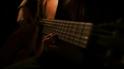 Guitar neck, strings, cinematic, dark muted interior.hands playing music Video stock 292154324