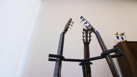 Guitar necks shine in perfect alignment on stand in music room Stock Footage 303105849