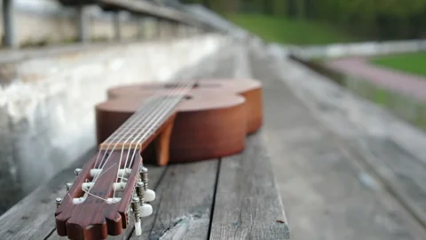 Guitar on an old park bench outside Video stock 274347296