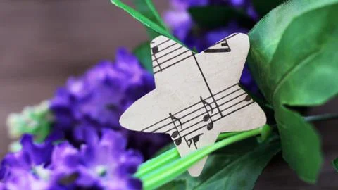 A guitar with paper star notes so close. Flowers background. Stock Photos