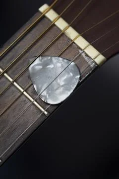 Guitar pick held between strings on neck. Guitar plectrum. Musical instruments. 스톡 사진
