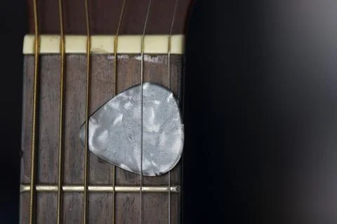 Guitar pick held between strings on neck. Guitar plectrum. Musical instruments. 스톡 사진