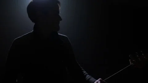 Guitar player medium shot with a single light in the background Stock-Footage 82406307