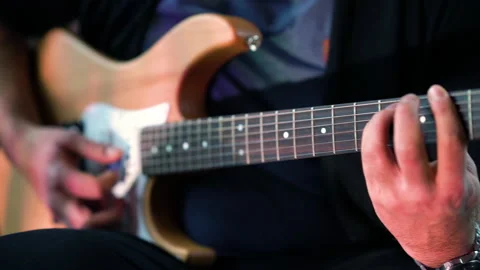 Guitar player sitting playing slowly e-guitar focus fingers | 4K Stock Footage 157812992