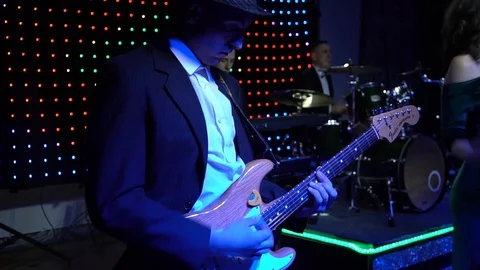 The guitar player is very active on stage with his rock band. Medium close-up Stock Footage 91684229
