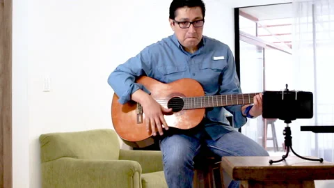 Guitar teacher teaching an online class Stock Footage 147229768