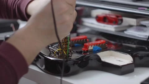 Guitar tech solders the electronics, repair of the musical instruments at the Stock Footage 281007976