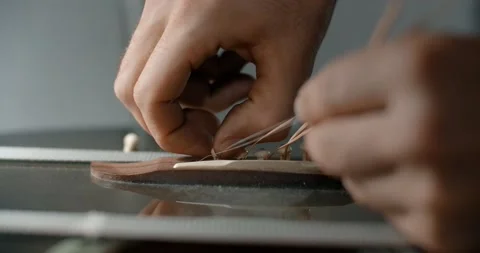 Guitar tech takes off the old strings from the guitar, luthier restrings the Stock Footage 164303093
