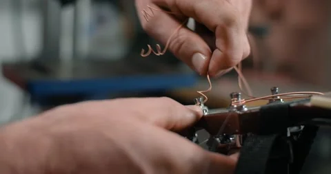 Guitar tech takes off the old strings from the guitar tuners, changing the Video stock 164523330
