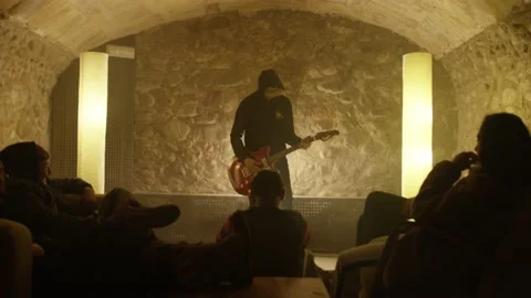 A guitarist performs in a bar in front of a group of friends Stock Footage 194748960