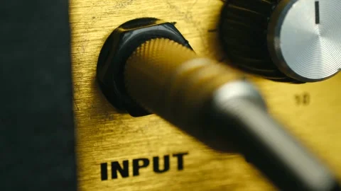 Guitarist plugging jack cable into amplifier input Stock Footage 321736722