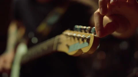 Guitarist turning knobs on fretboard in studio. Man holding guitar in hall. 스톡 동영상 140362522