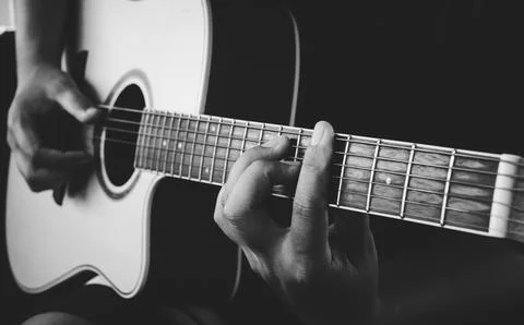 Guitarist's hand on strings on dark background Stock Photos