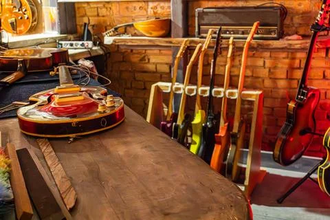 Guitars in Workshop Assembly with Rustic Brick Wall Background Stock Photos